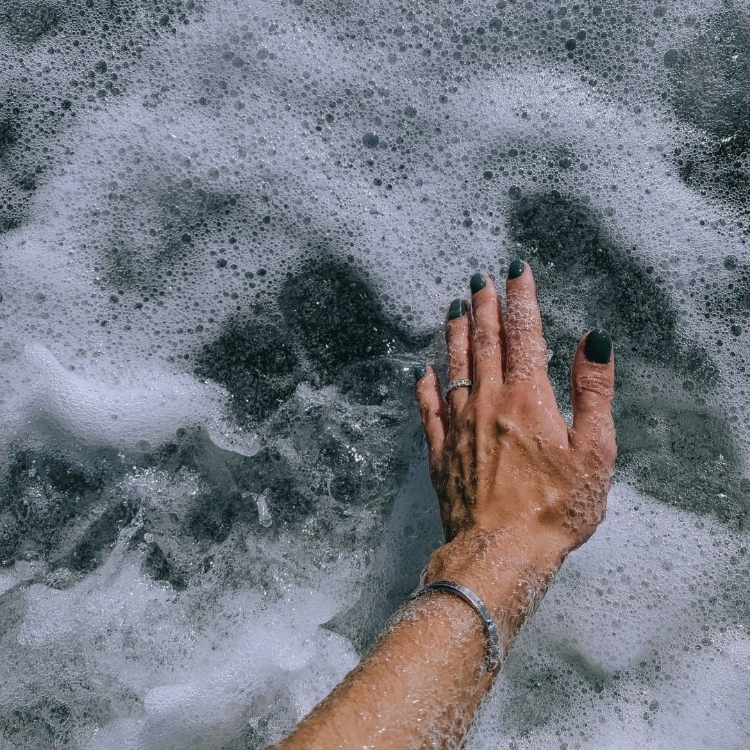 A hand resting in sea foam